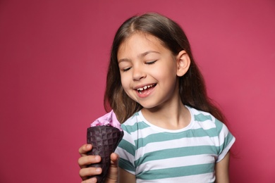 Photo of Adorable little girl with delicious ice cream against color background