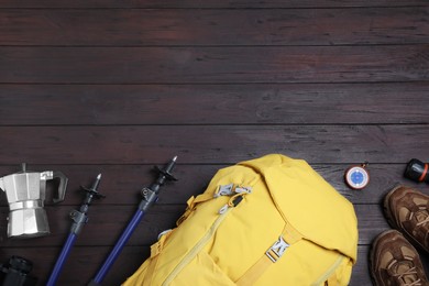 Photo of Flat lay composition with tourist backpack and other camping equipment on wooden background, space for text
