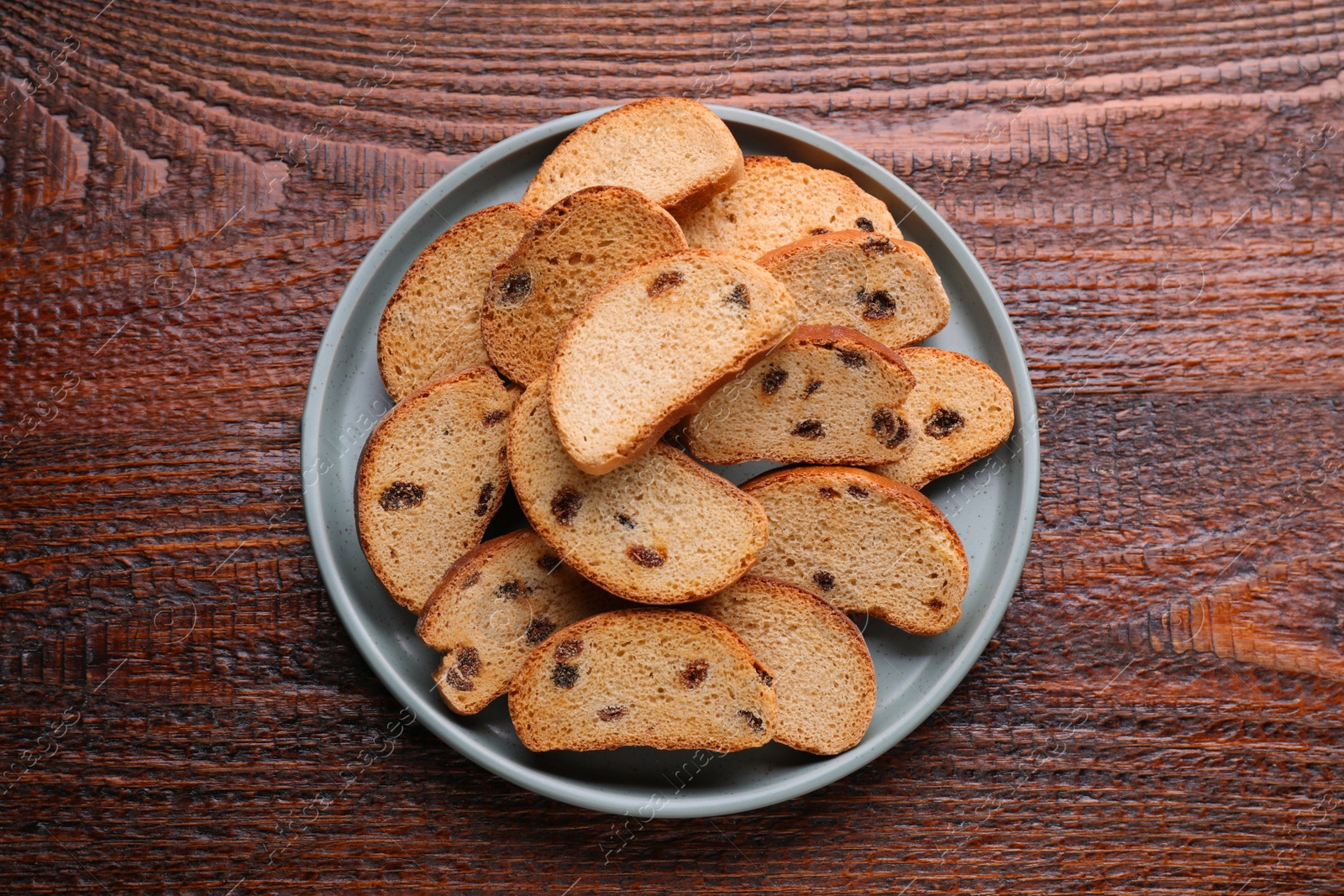 Photo of Plate of sweet hard chuck crackers with raisins on wooden table, top view