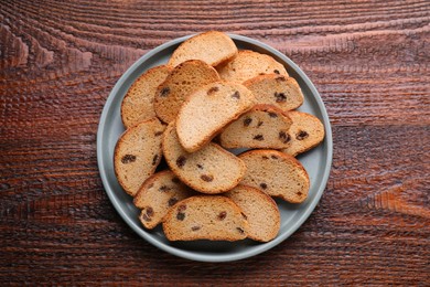 Photo of Plate of sweet hard chuck crackers with raisins on wooden table, top view