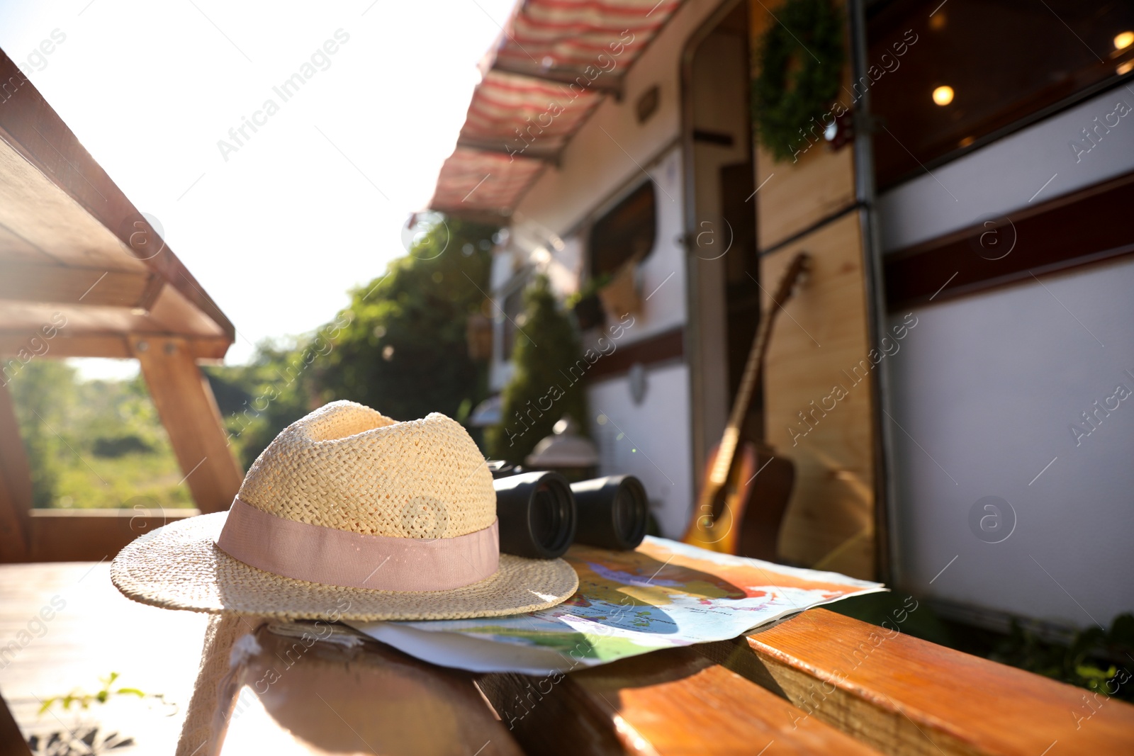 Photo of Hat and travel accessories on wooden table near motorhome. Summer trip