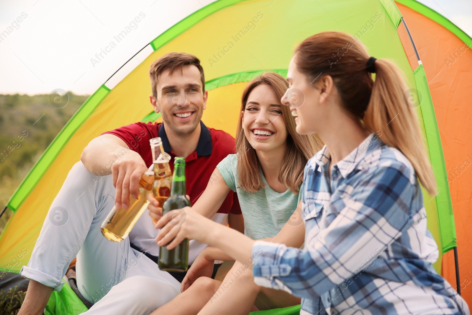 Photo of Group of young people with beer in wilderness. Camping season