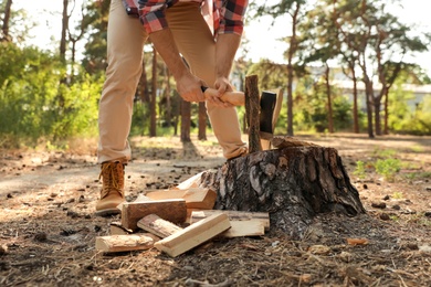 Man chopping firewood with axe in forest, closeup