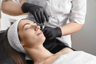 Photo of Cosmetologist giving lips injection to patient in clinic, closeup. Cosmetic surgery