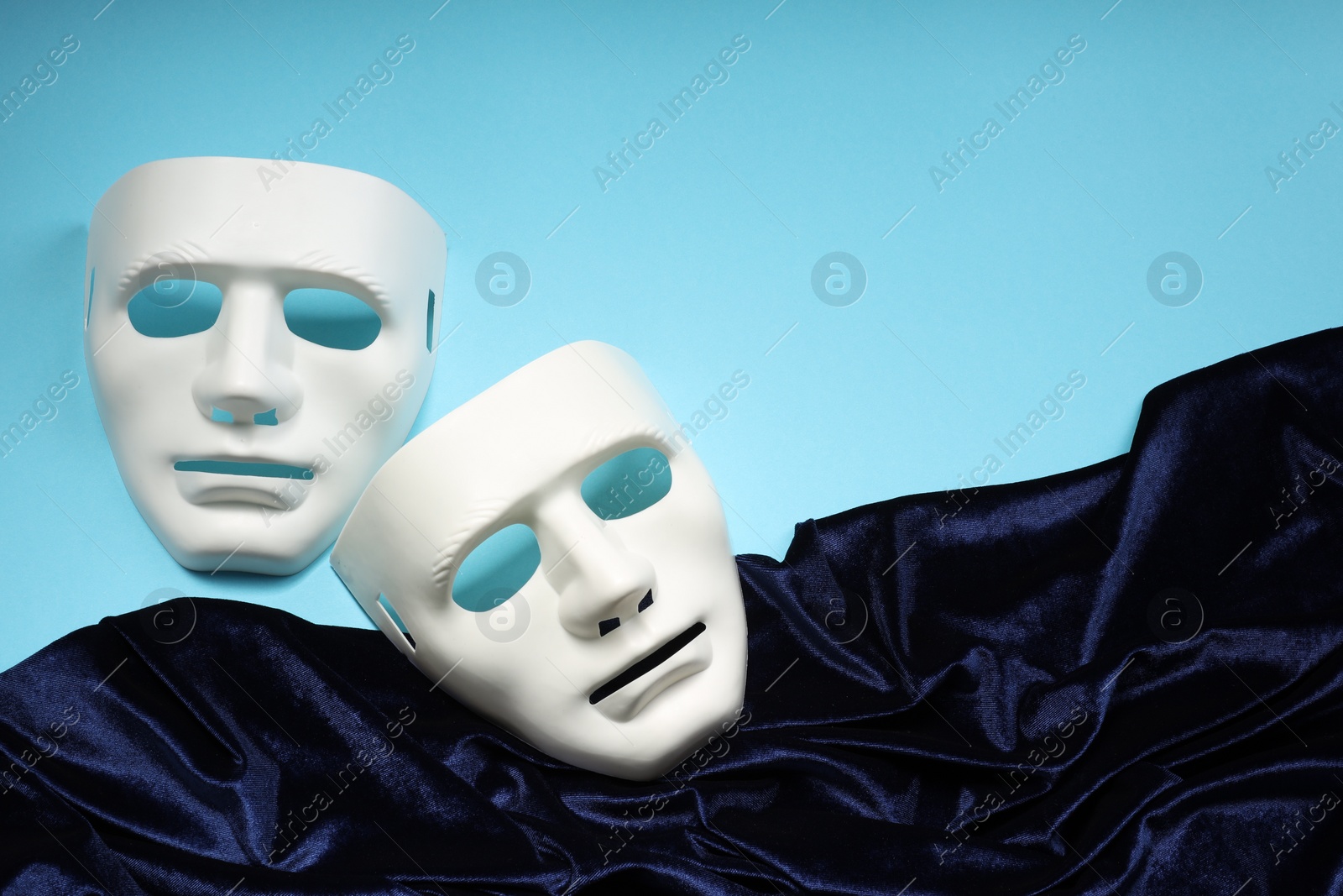 Photo of Theater arts. White masks and fabric on light blue background, above view. Space for text