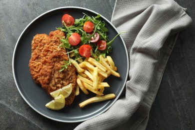 Photo of Tasty schnitzels served with potato fries, tomatoes and arugula on grey table, top view