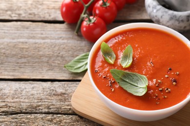 Photo of Delicious tomato soup on wooden table, space for text