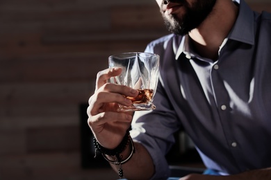 Photo of Man with glass of whiskey at home, closeup. Space for text