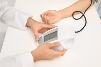 Young doctor checking patient's blood pressure in hospital