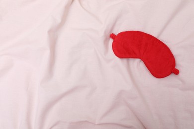 Photo of Red sleep mask on beige cloth, top view. Space for text