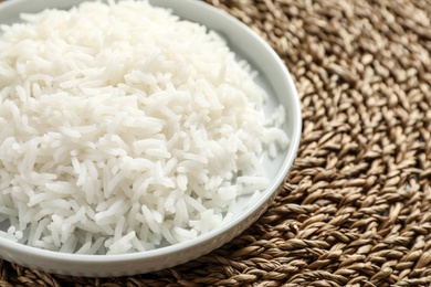 Photo of Plate of tasty cooked rice on wicker mat, closeup. Space for text