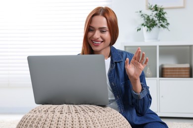 Photo of Woman waving hello during video chat via laptop at home