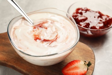 Photo of Tasty yoghurt with jam and strawberry on grey table, closeup