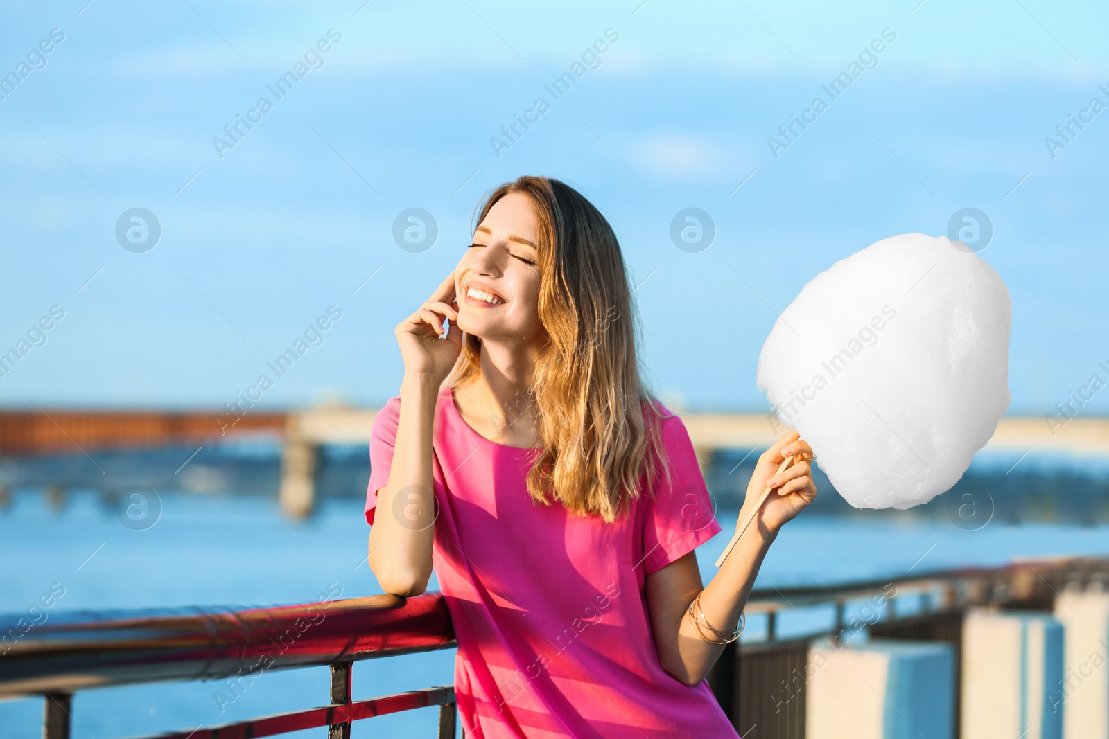 Photo of Happy young woman with cotton candy on waterfront