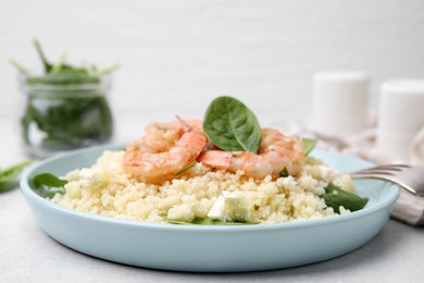 Photo of Delicious couscous with shrimps and spinach served on white table, closeup