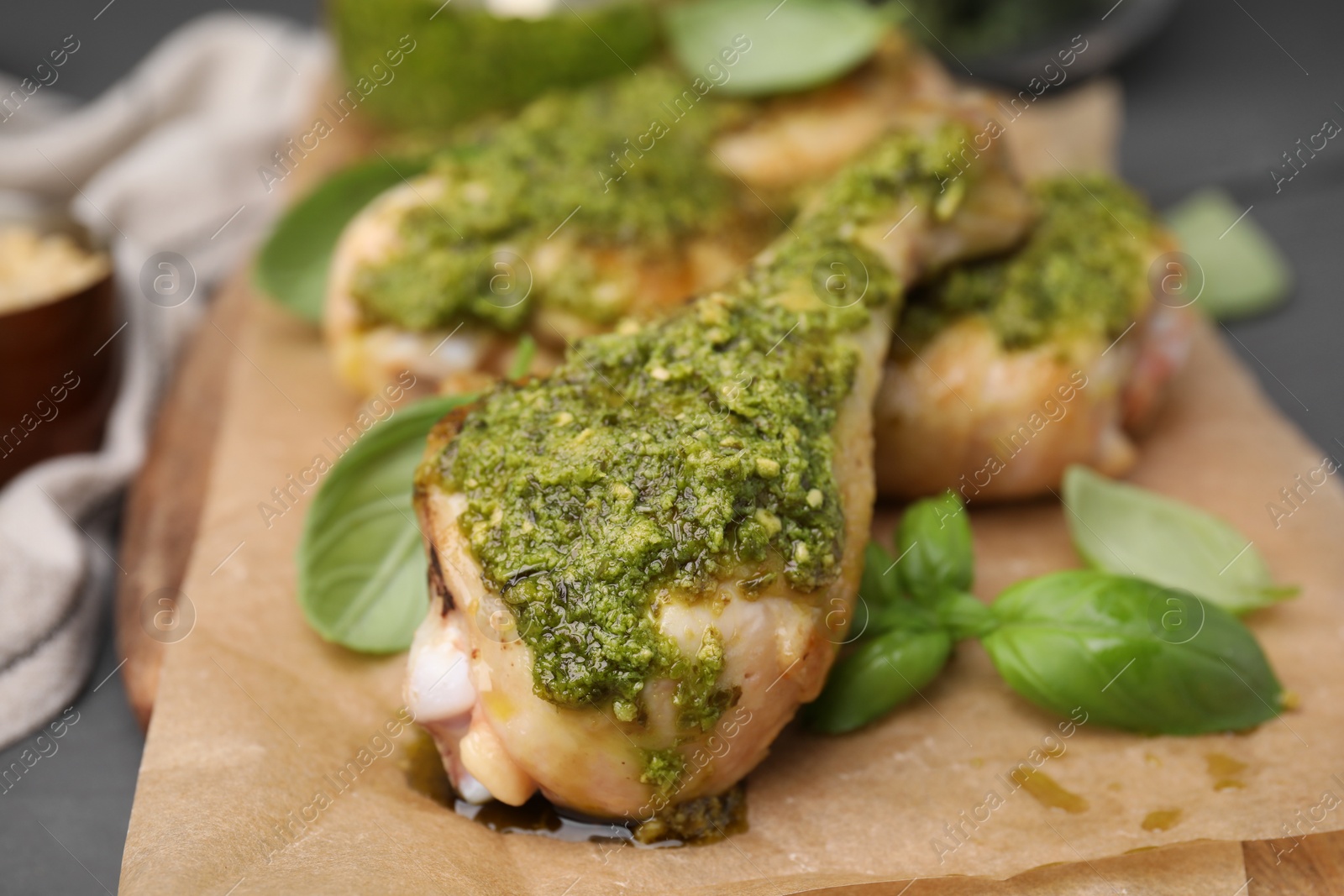 Photo of Delicious fried chicken drumsticks with pesto sauce and basil on table, closeup