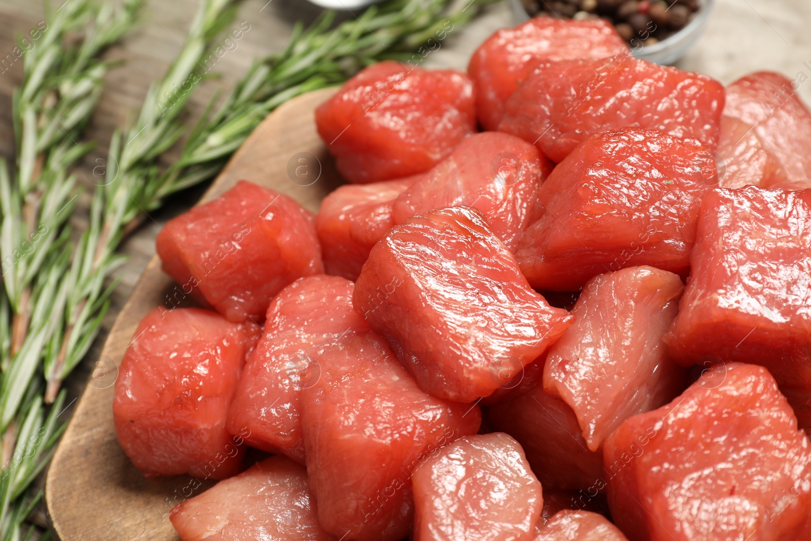 Photo of Cooking delicious goulash. Raw beef meat and rosemary on wooden board, closeup