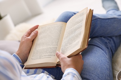 Photo of Woman reading hardcover book at home, closeup