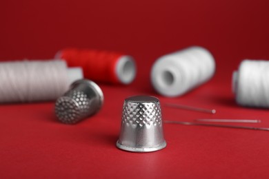 Photo of Silver thimble on red background. Sewing accessories