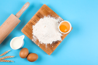 Flat lay composition with eggs and other ingredients on light blue background. Baking pie