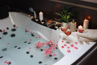 Photo of Bathtub with glasses of wine and candles indoors. Romantic atmosphere