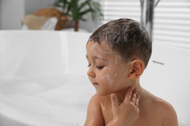 Cute little boy washing hair with shampoo in bathroom. Space for text