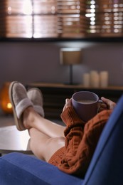 Woman with cup of aromatic coffee relaxing at home, closeup