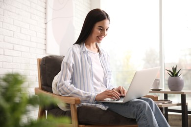 Photo of Beautiful young woman using laptop at home