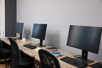 Photo of Open office interior. Modern workplaces with computers near light grey wall