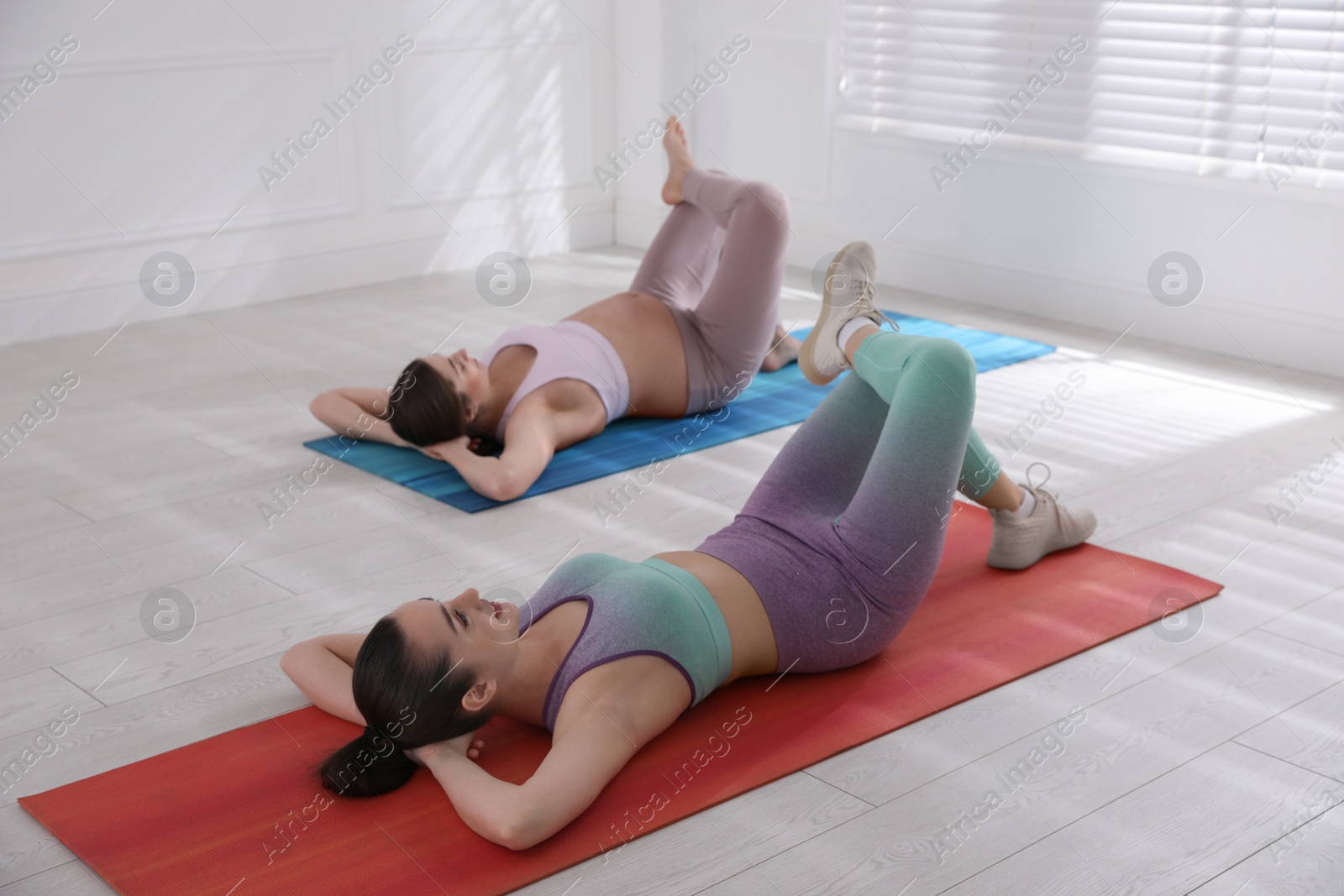 Photo of Trainer working with pregnant woman in gym. Preparation for child birth