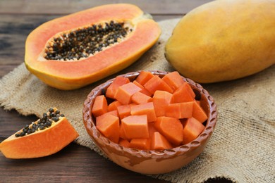 Photo of Tasty whole and cut papaya fruits on wooden table