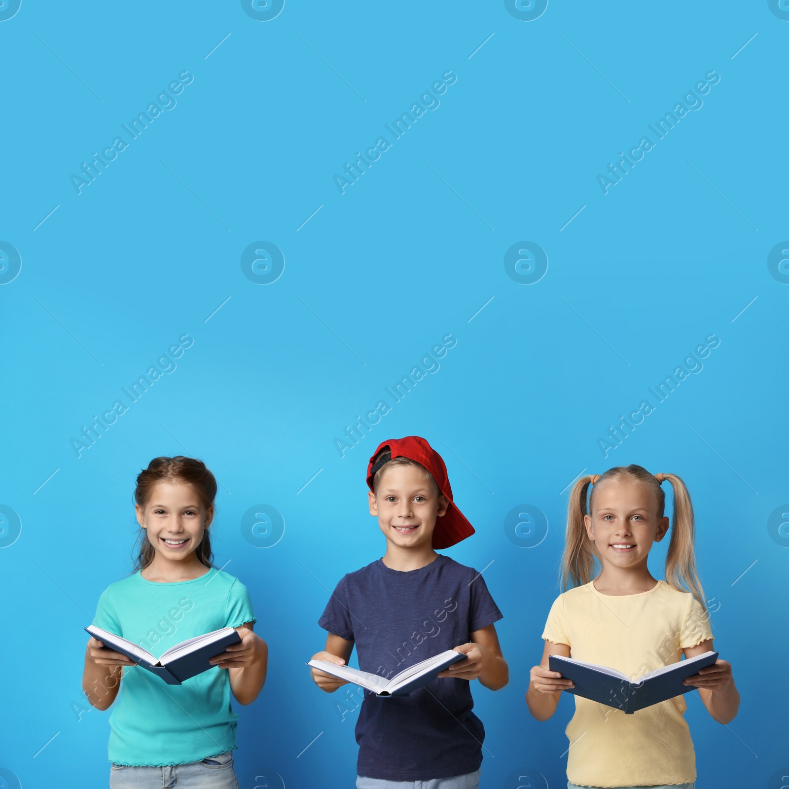 Photo of Portrait of little children reading books on blue background