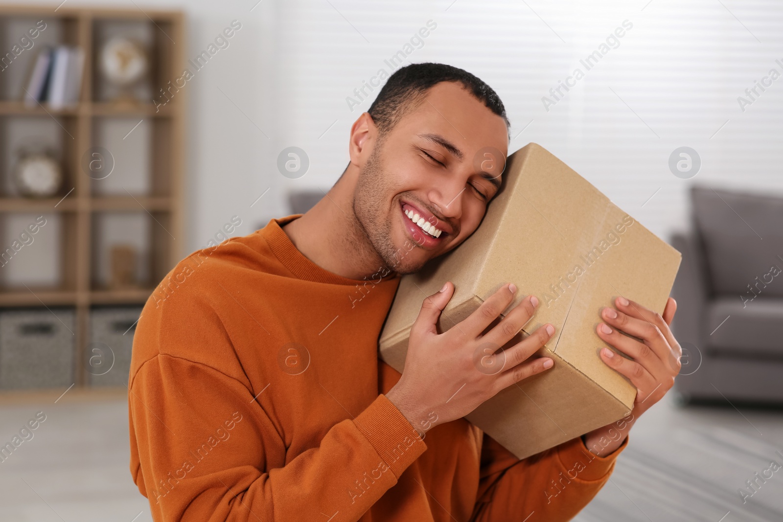 Photo of Happy young man with parcel at home. Internet shopping