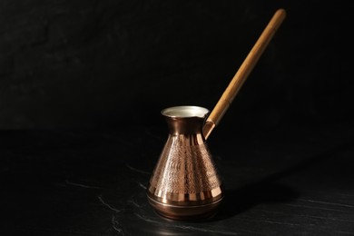 Photo of Beautiful copper turkish coffee pot with wooden handle on black table