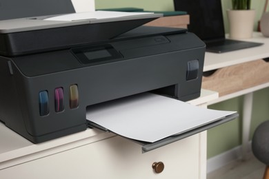 Photo of Modern printer with paper on white chest of drawers indoors, closeup