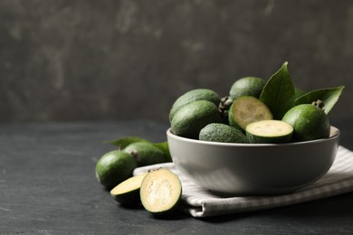 Fresh green feijoa fruits on black table, space for text