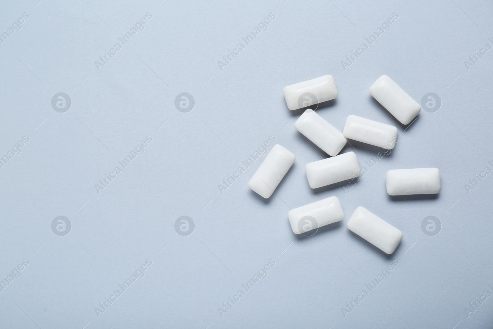 Photo of Tasty white chewing gums on light grey background, flat lay. Space for text