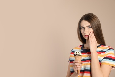 Emotional young woman with sensitive teeth and ice cream on color background. Space for text