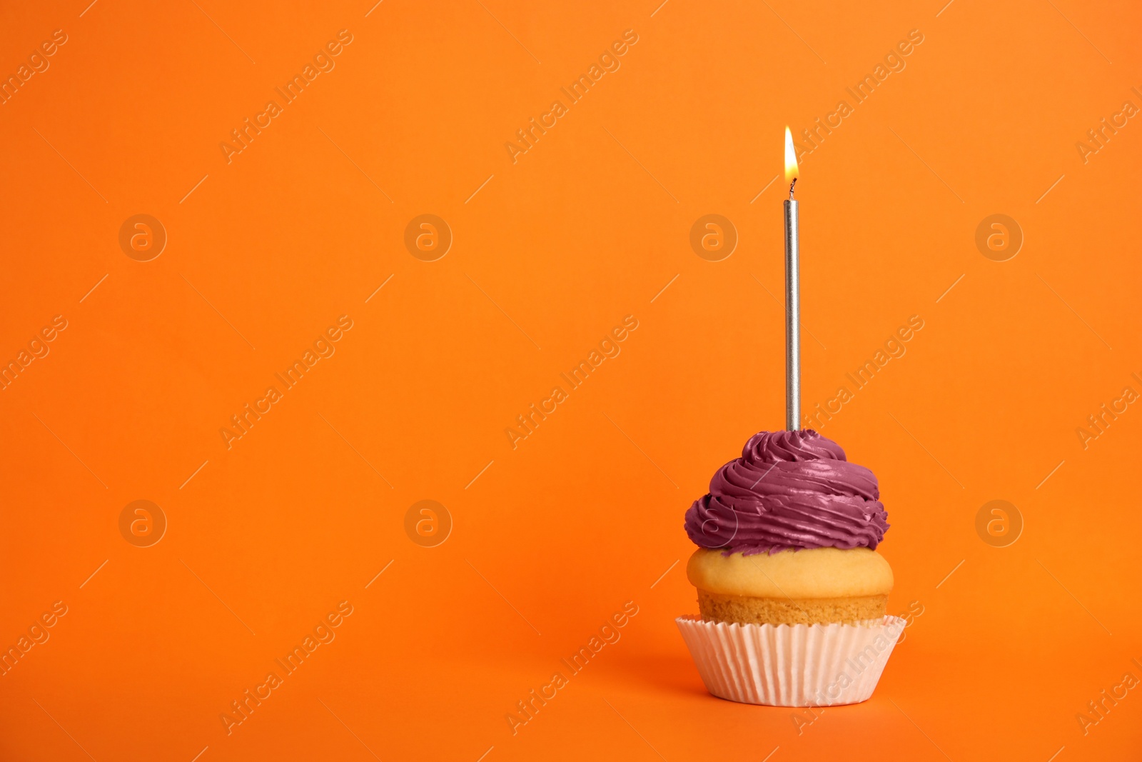 Photo of Birthday cupcake with candle on orange background, space for text