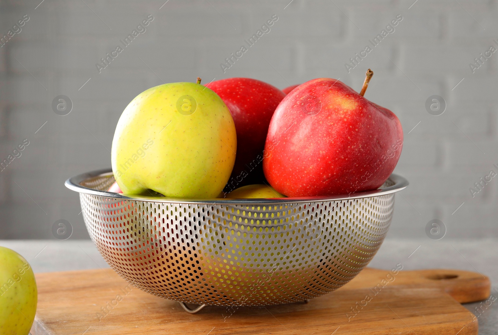 Photo of Fresh ripe apples in colander on table, closeup