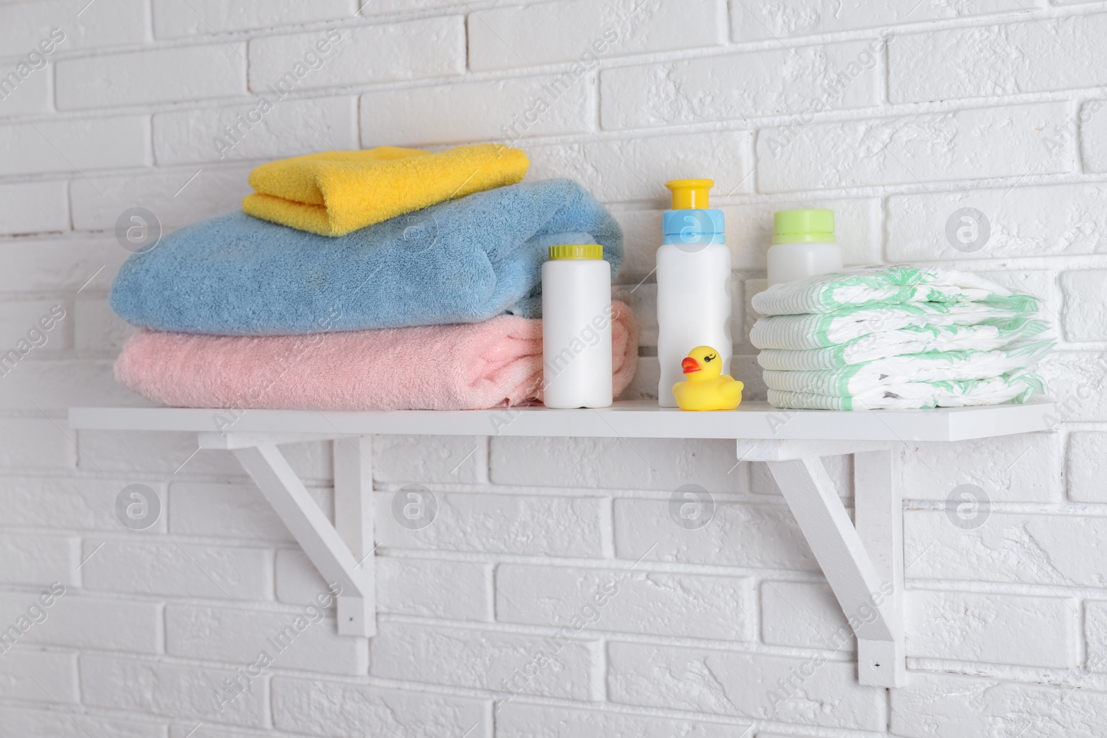 Photo of Shelf with baby accessories on white brick wall