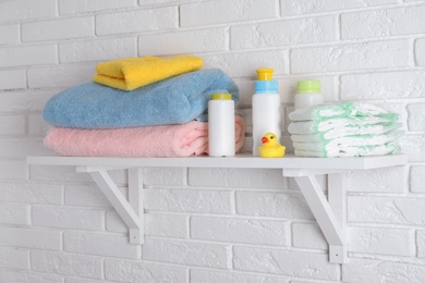 Shelf with baby accessories on white brick wall