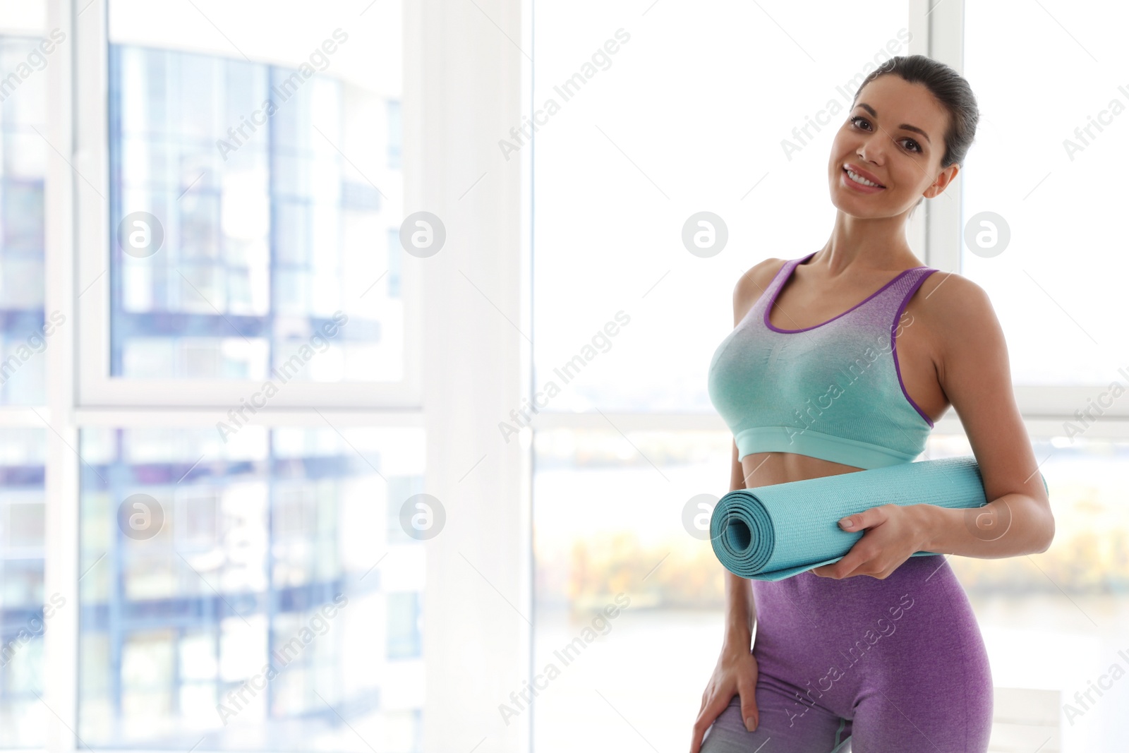 Photo of Young woman with yoga mat in light gym