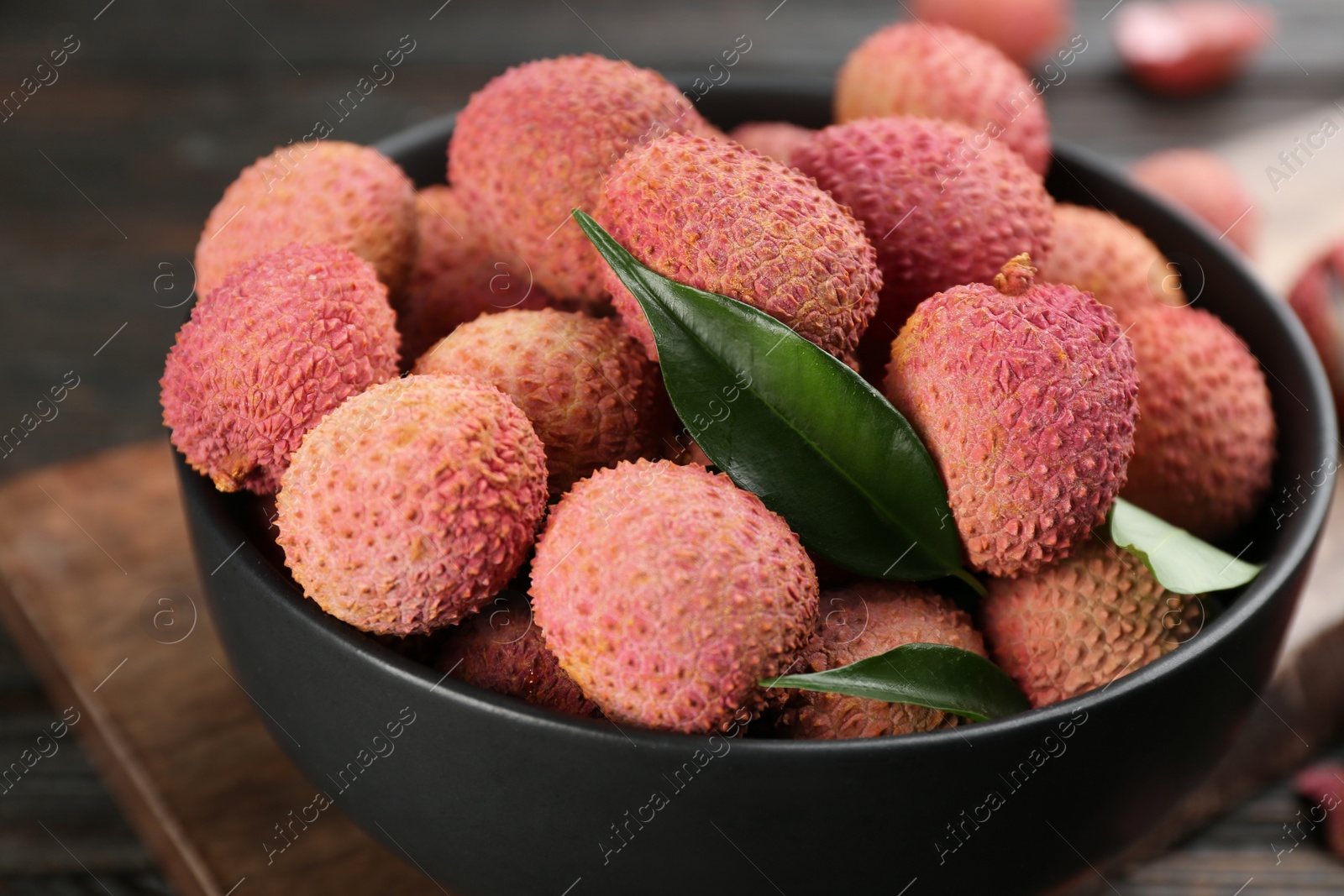 Photo of Fresh ripe lychee fruits in bowl on table, closeup