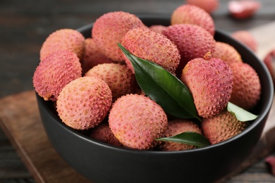 Photo of Fresh ripe lychee fruits in bowl on table, closeup