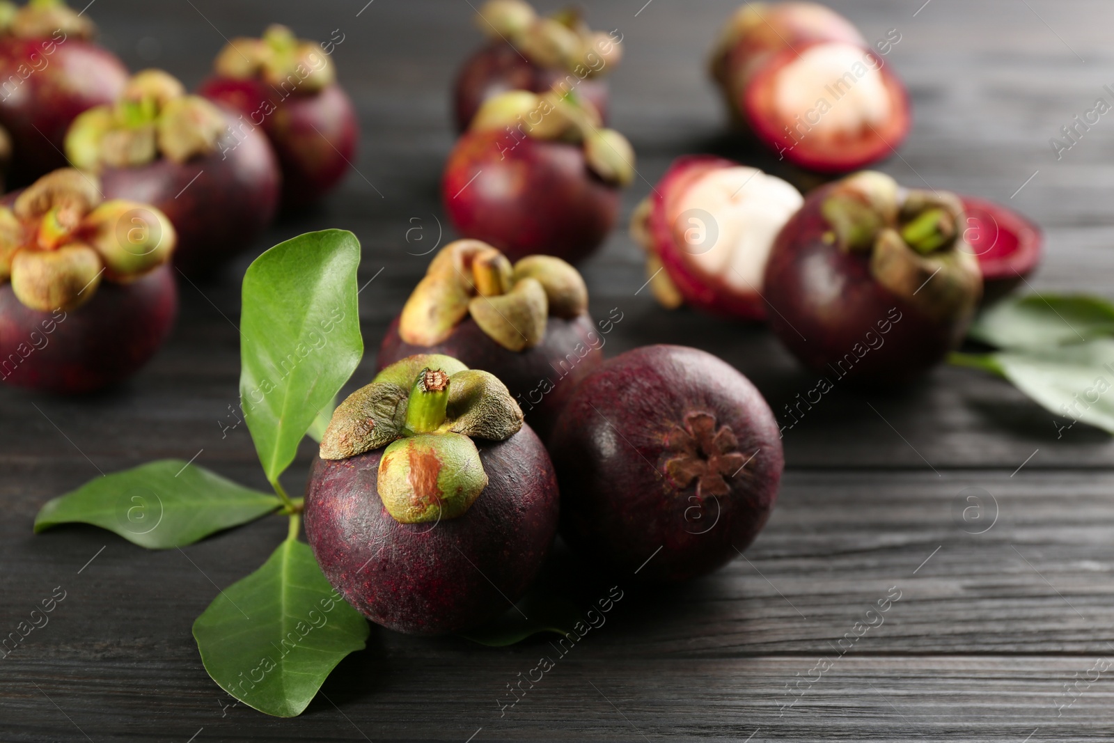 Photo of Fresh ripe mangosteen fruits on dark wooden table