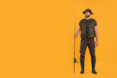 Fisherman with fishing rod on yellow background, space for text