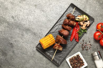 Delicious shish kebabs with vegetables and spices on grey textured table, flat lay. Space for text