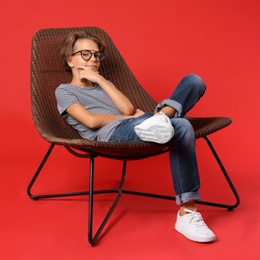 Photo of Cute little boy sitting in chair on red background