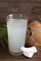 Photo of Glass of coconut water, leaf and nuts on wooden table